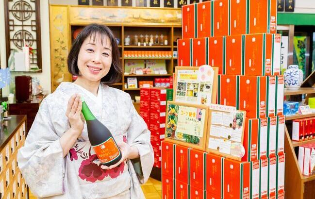 様々な漢方薬がずらりと並ぶ店内。 鷺岡さんが手にしているのはオリジナルの酵素ドリンク 「サギオカコーソ」＝丸亀市中府町の鷺岡漢方堂薬局