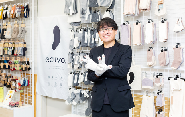 ファッション手袋など自社ブランド商品が並ぶサンプルルーム。福﨑さんが着けているのは人気ブランド「ecuvo, (エクボ)」。 指先にスリットが入っているため、スマホの操作も可能＝東かがわ市白鳥のフクシン本社