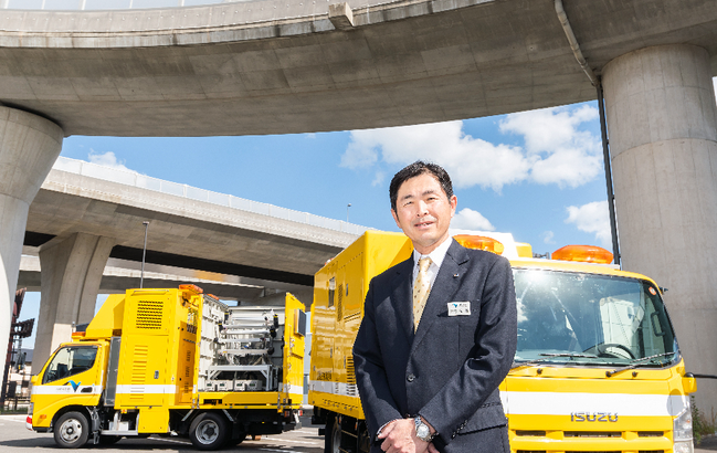 道路性状測定車「スマートイーグル」を背に ＝高松市林町の高松自動車道･高松中央IC