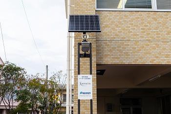 東日本大震災をきっかけに自社開発した蓄電池内蔵型「太陽光発電街路灯」。 非常時にUSBやコンセントが使用できる。太陽光発電無しで5日間の点灯が可能